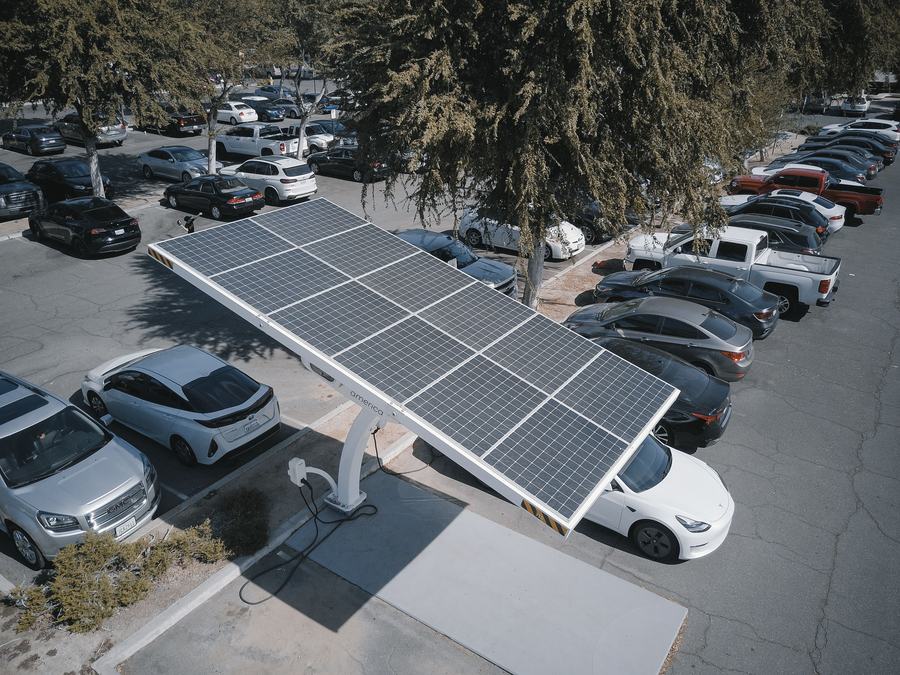 Voitures électriques en charge sous une ombrière à panneaux solaires sur un parking